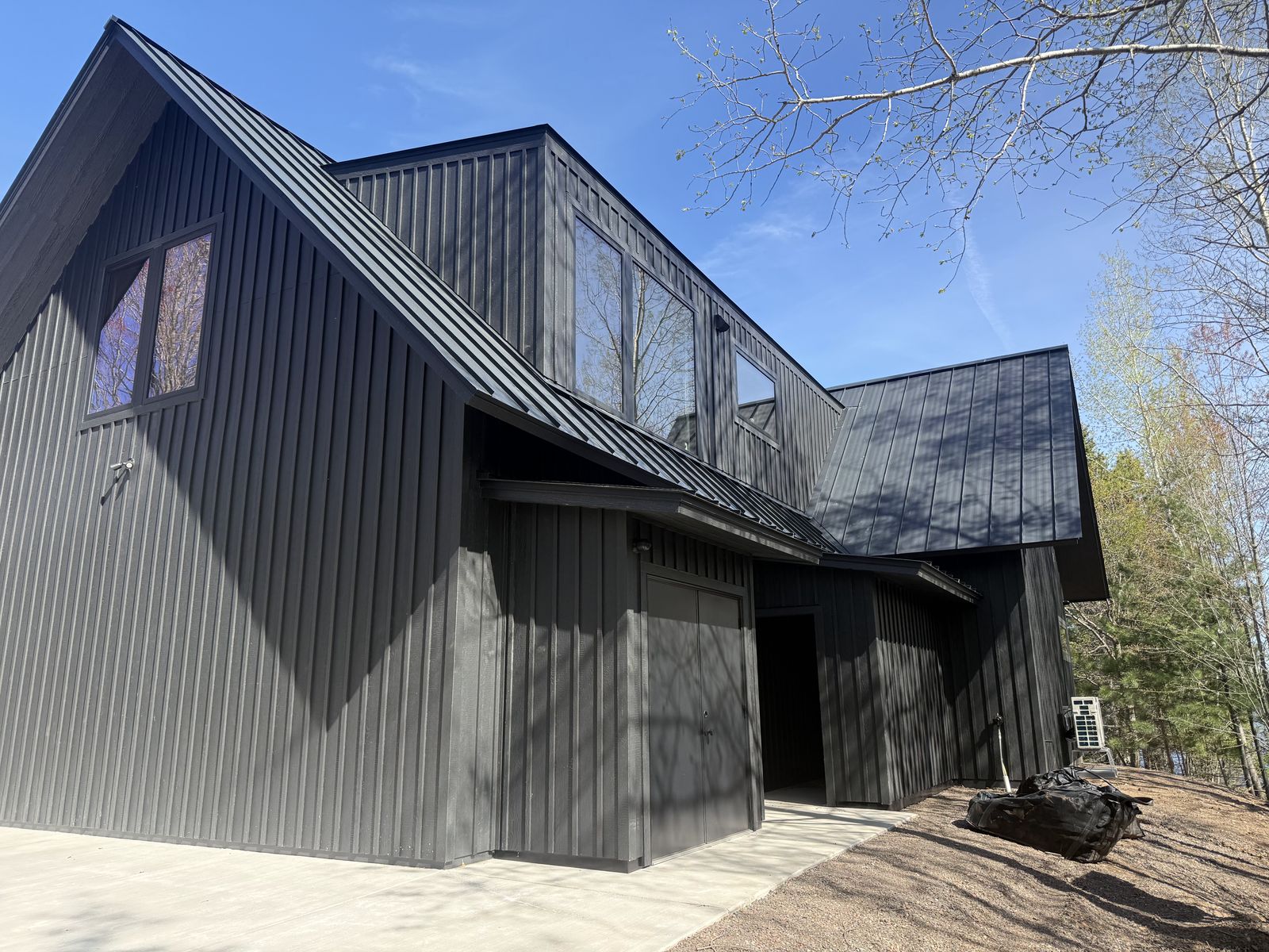 Modern black-gabled custom home exterior among bare spring birch at Island Lake, Northern Minnesota