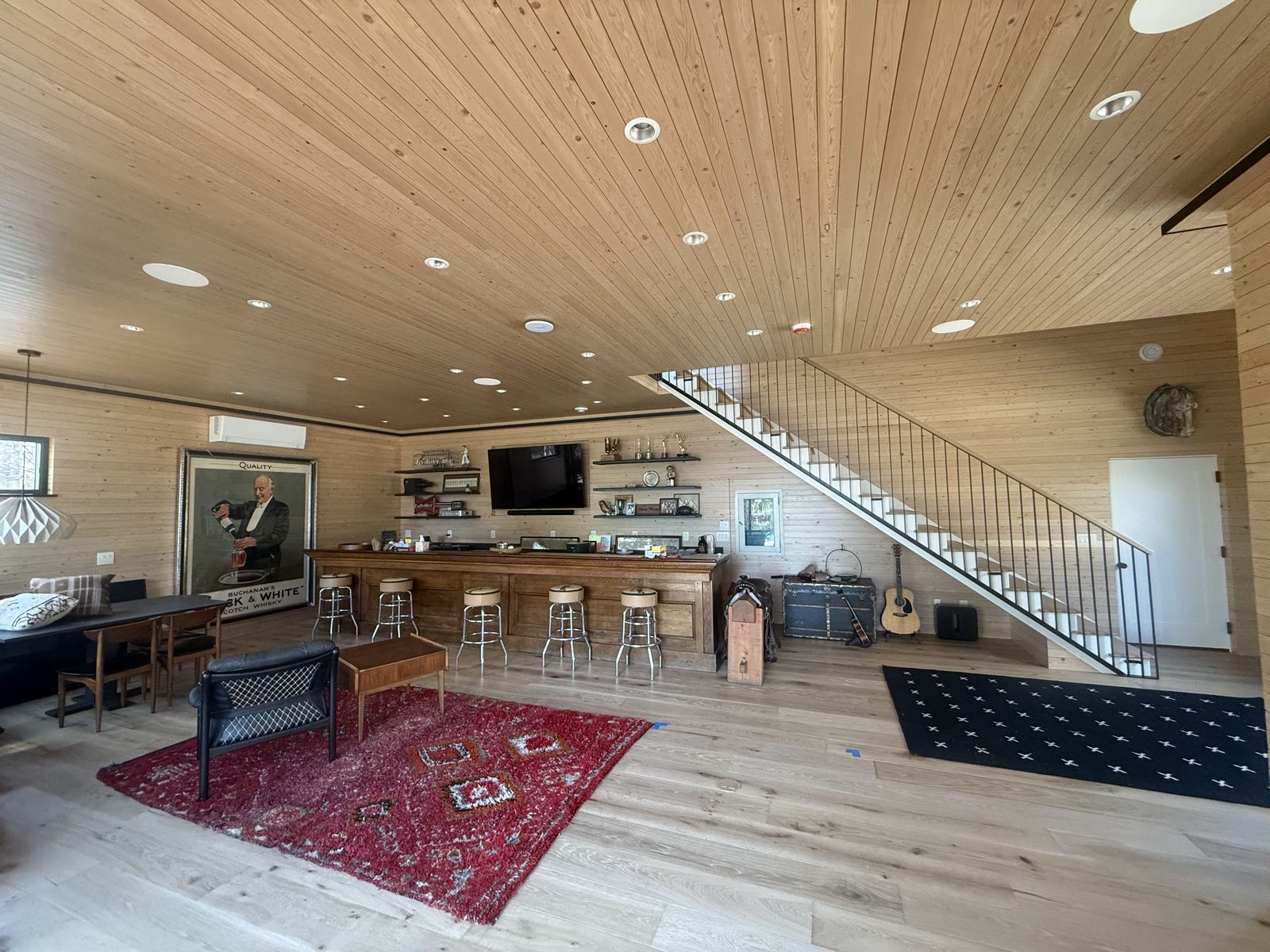 Open-concept great room with a vaulted tongue-and-groove wood ceiling and staircase in the Island Lake custom home
