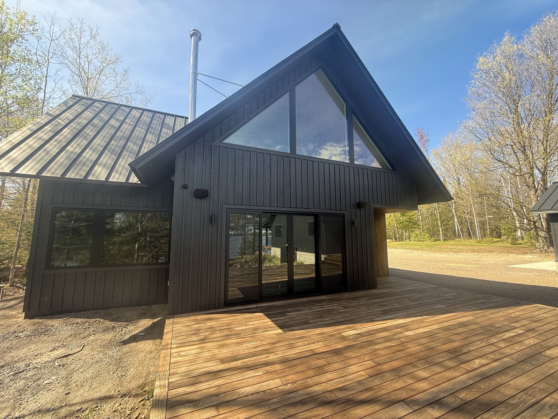 The Island Lake custom home — a modern black board-and-batten house with a thermally modified wood deck on a wooded lot near Duluth, Minnesota