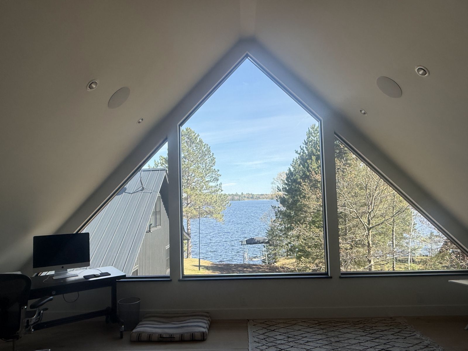 Peaked triangular window framing a lake view from the loft of the Island Lake home
